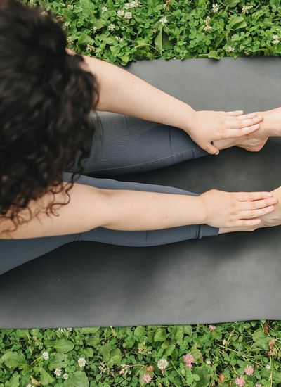 A serene individual stretching gently outdoors in a park setting.